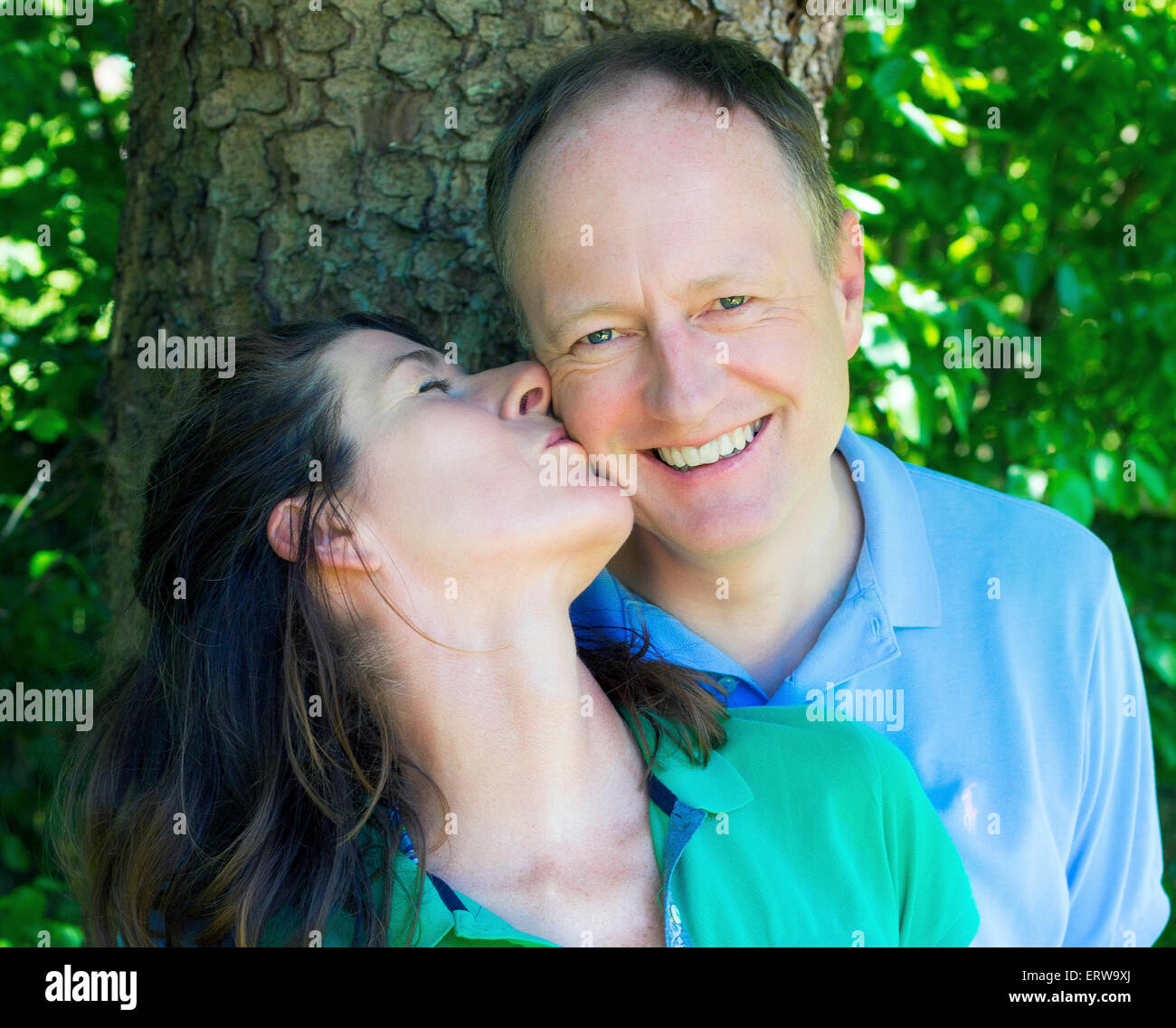 couple kissing in front of a tree Stock Photo - Alamy