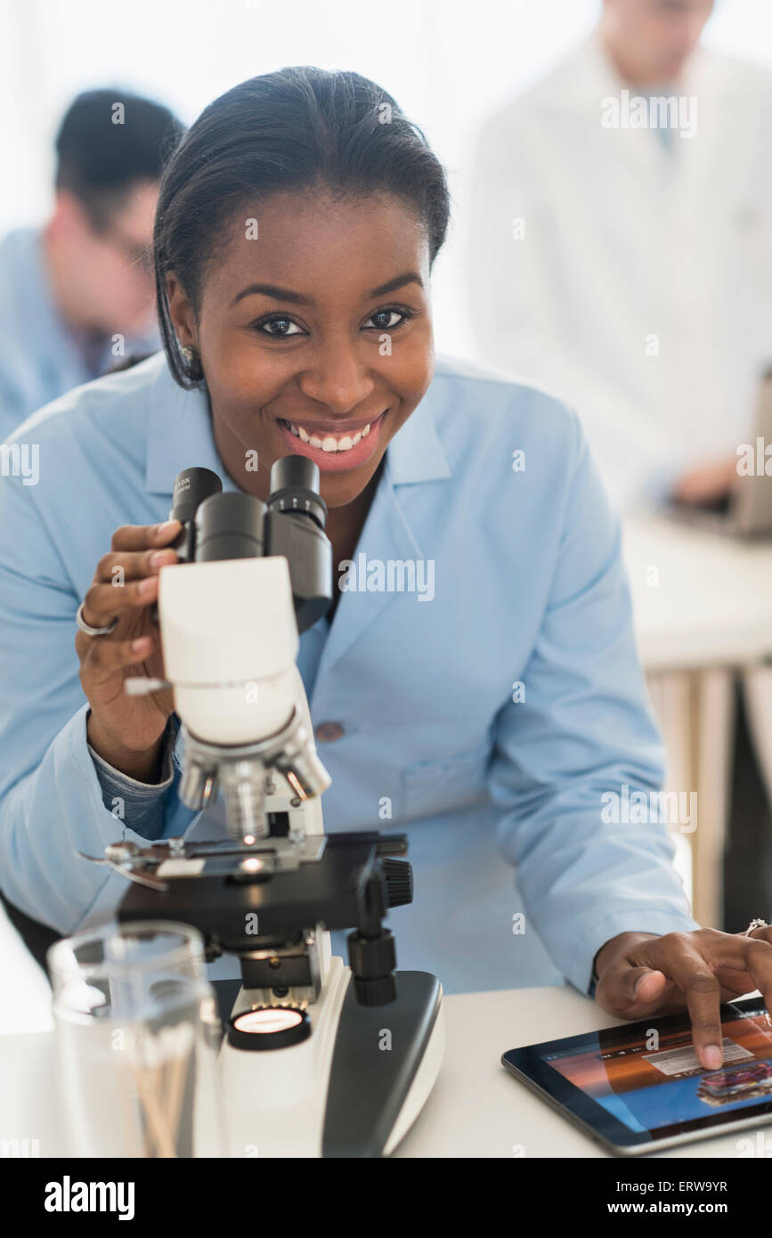 Scientist using microscope and digital tablet in research laboratory Stock Photo