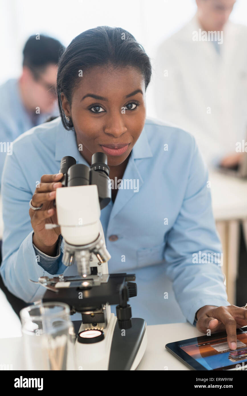 Scientist using microscope and digital tablet in research laboratory Stock Photo