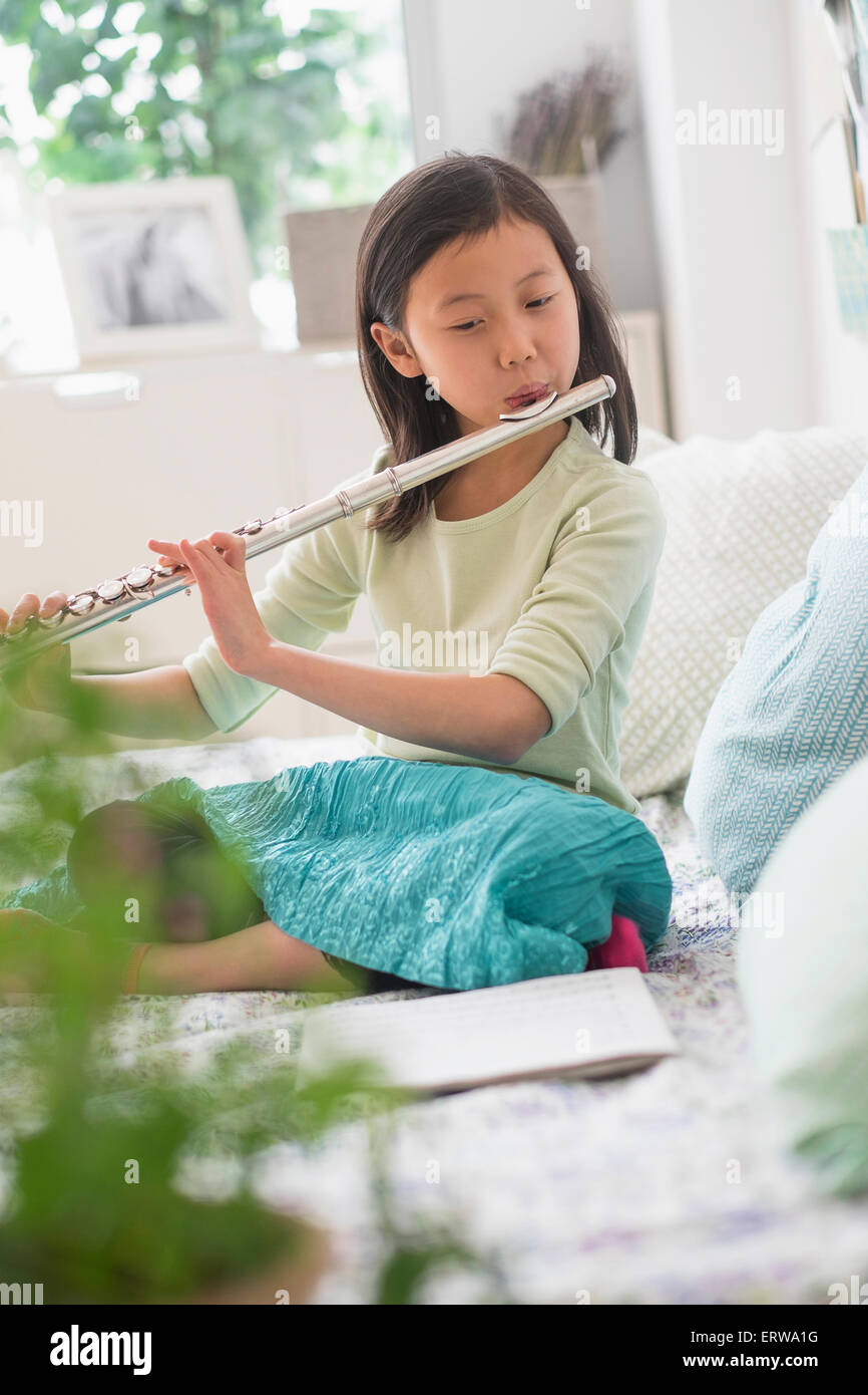 Chinese girl practicing flute on bed Stock Photo Alamy