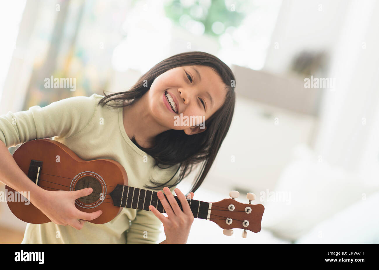 Chinese girl practicing ukulele in bedroom Stock Photo