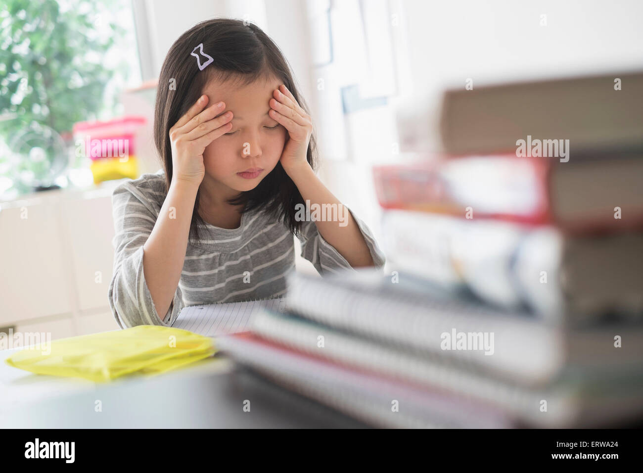 Anxious Chinese student rubbing forehead doing homework Stock Photo