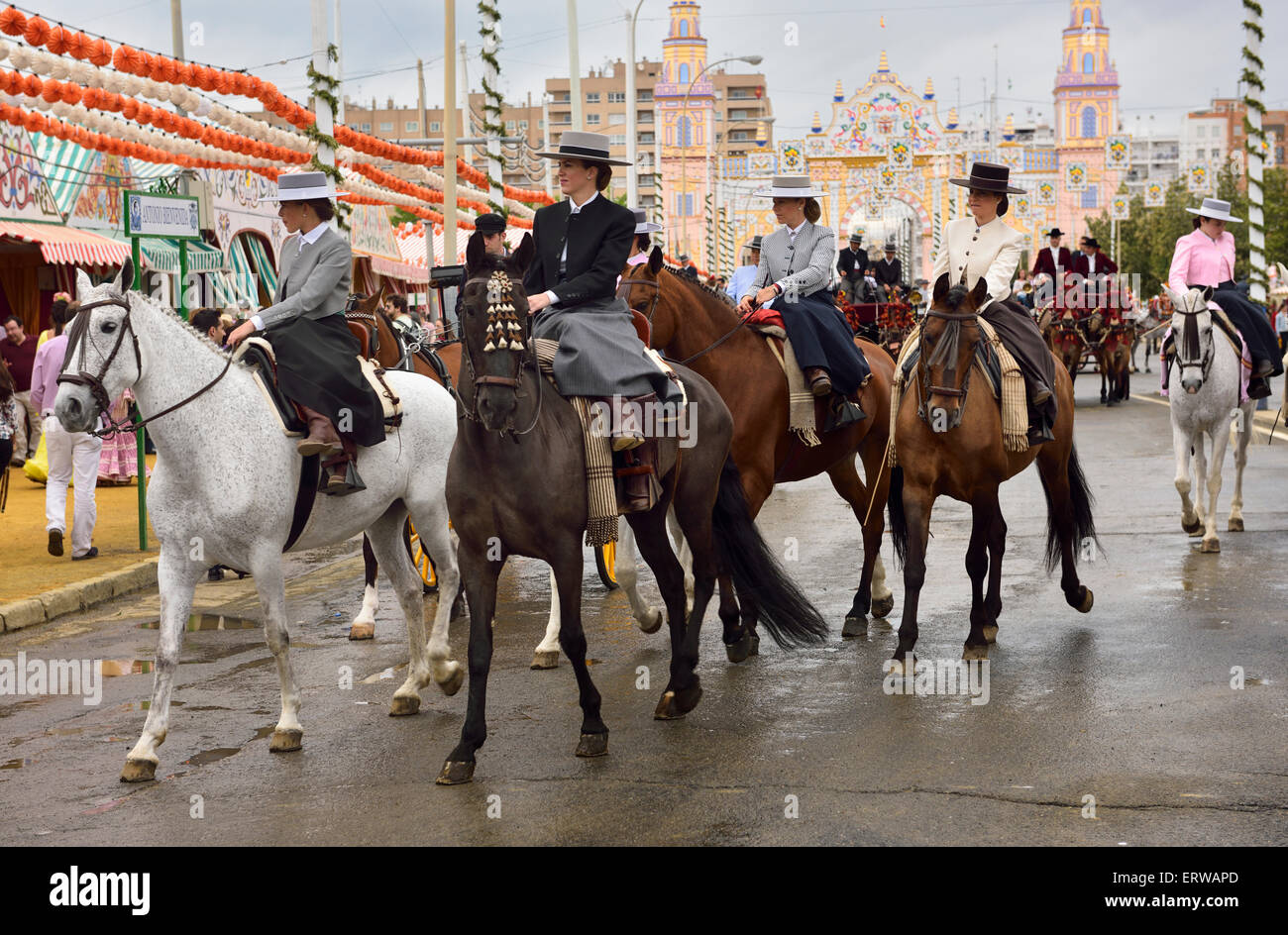 Women on horseback riding sidesaddle on Antonio Bienvenida street with Main Gate 2015 Seville April Fair Stock Photo