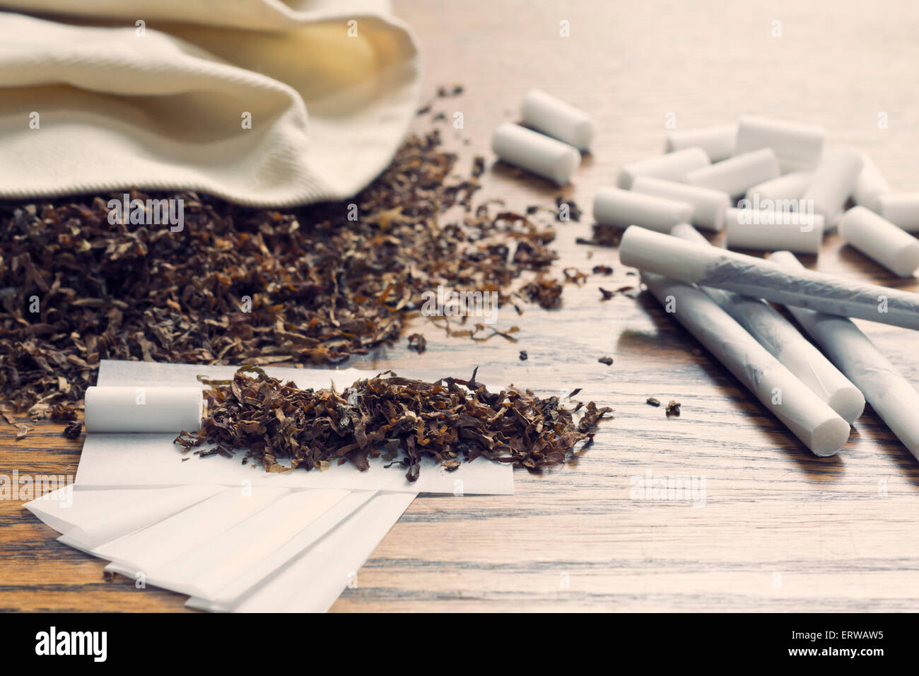 Rolling cigarettes with filters papers and plenty finely cut tobacco Stock  Photo