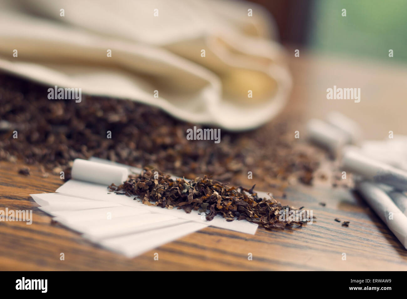 Rolling cigarettes with filters papers and plenty finely cut tobacco Stock  Photo