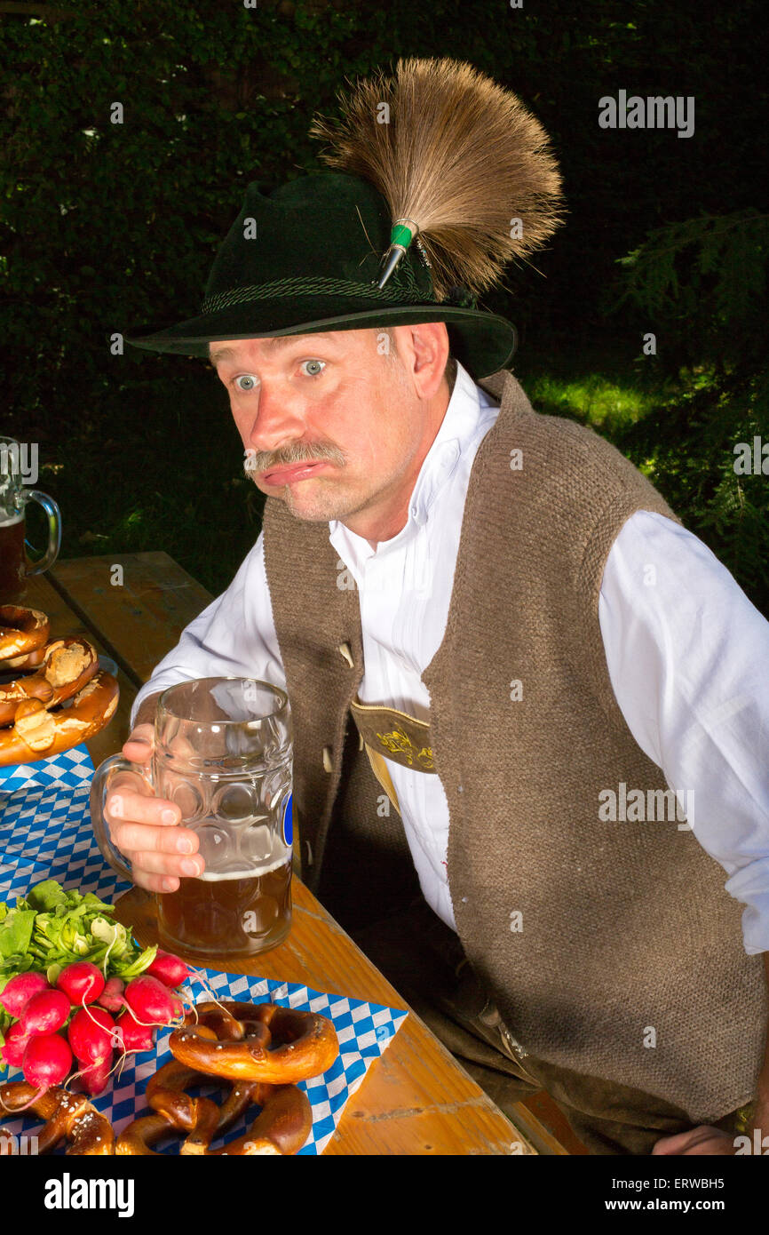 bavarian man sitting on bench with a beer mug and is drunk Stock Photo