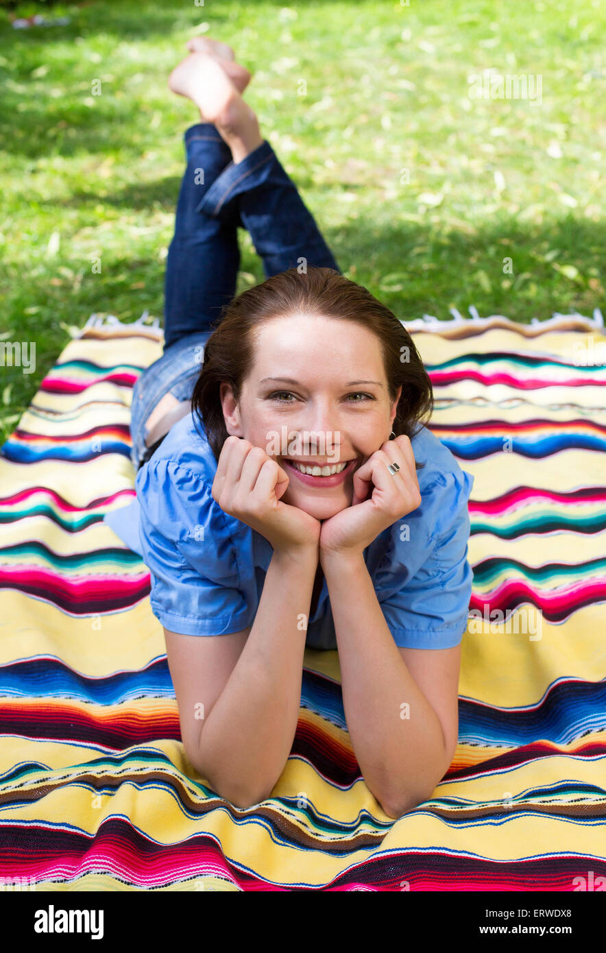 young woman is lying on a blanket on grass and smiles Stock Photo Alamy
