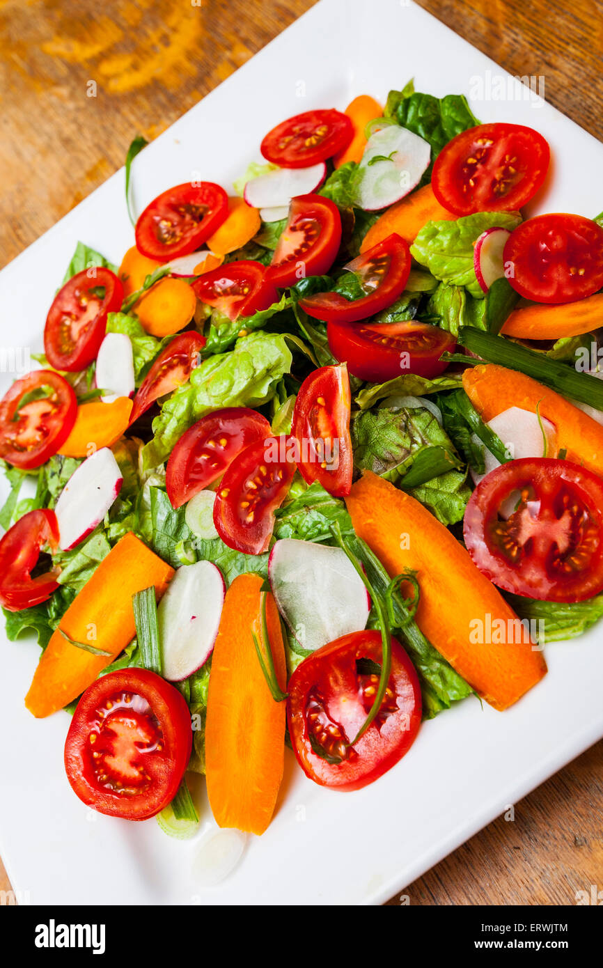 A tossed Salad with green lettuce, romaine, tomato, carrot, green onion, and radish. Stock Photo