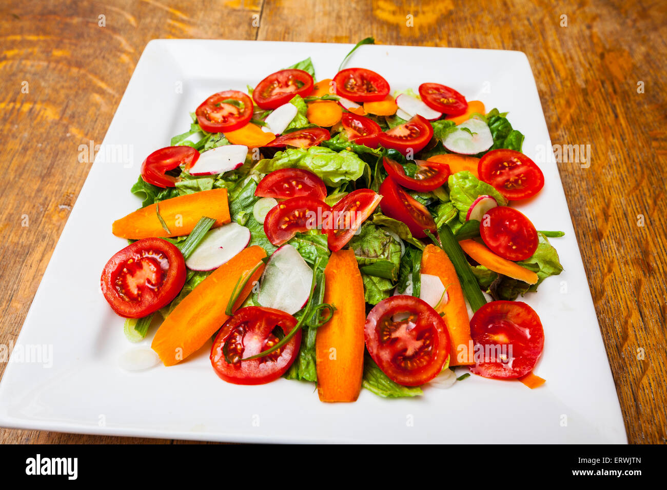A tossed Salad with green lettuce, romaine, tomato, carrot, green onion, and radish. Stock Photo