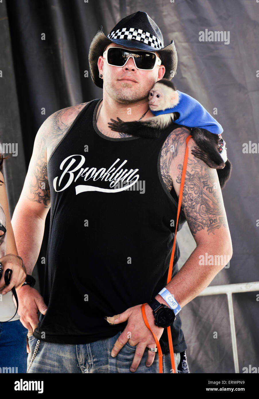 A man wearing a cowboy hat with a monkey hugging his neck. Stock Photo