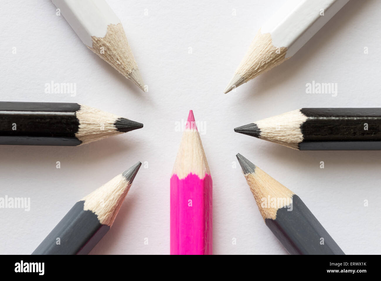 Pink pencil surrounded by black, gray and white pencils Stock Photo