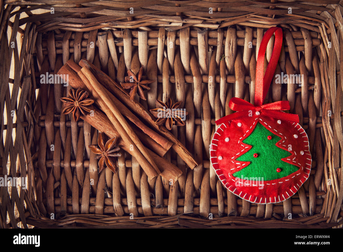 Christmas handmade red toy with tree from felt, cinnamon and star anise in brown twiggen basket Stock Photo
