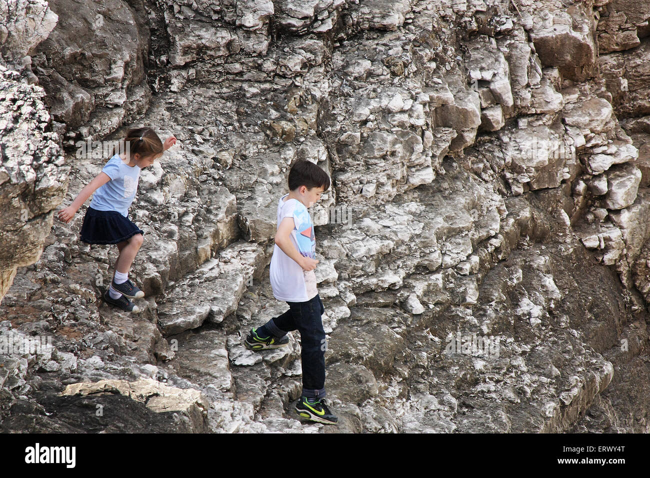 Young people on cliff face path in dangerous conditions. Stock Photo