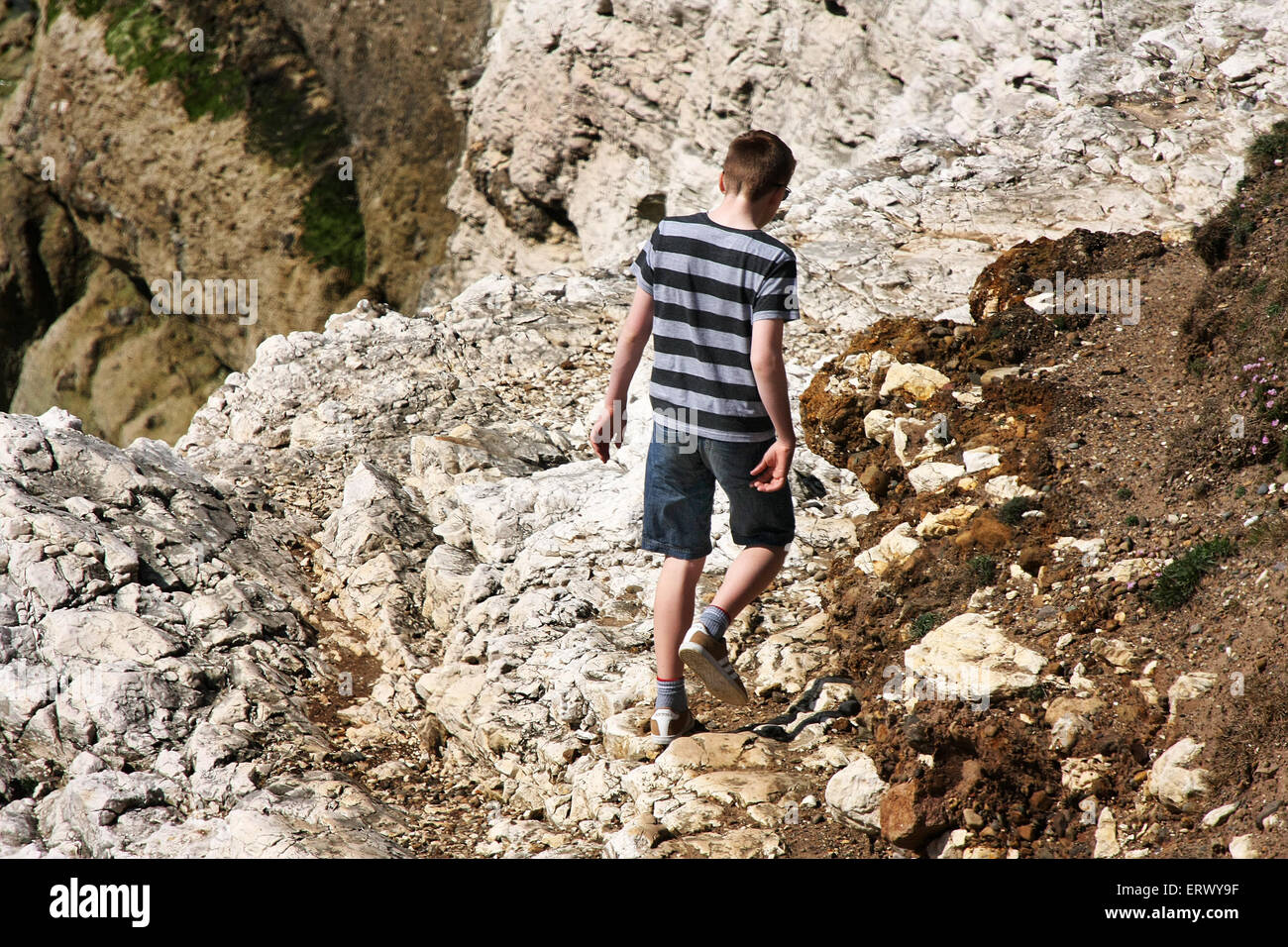 Young people on cliff face path in dangerous conditions. Stock Photo