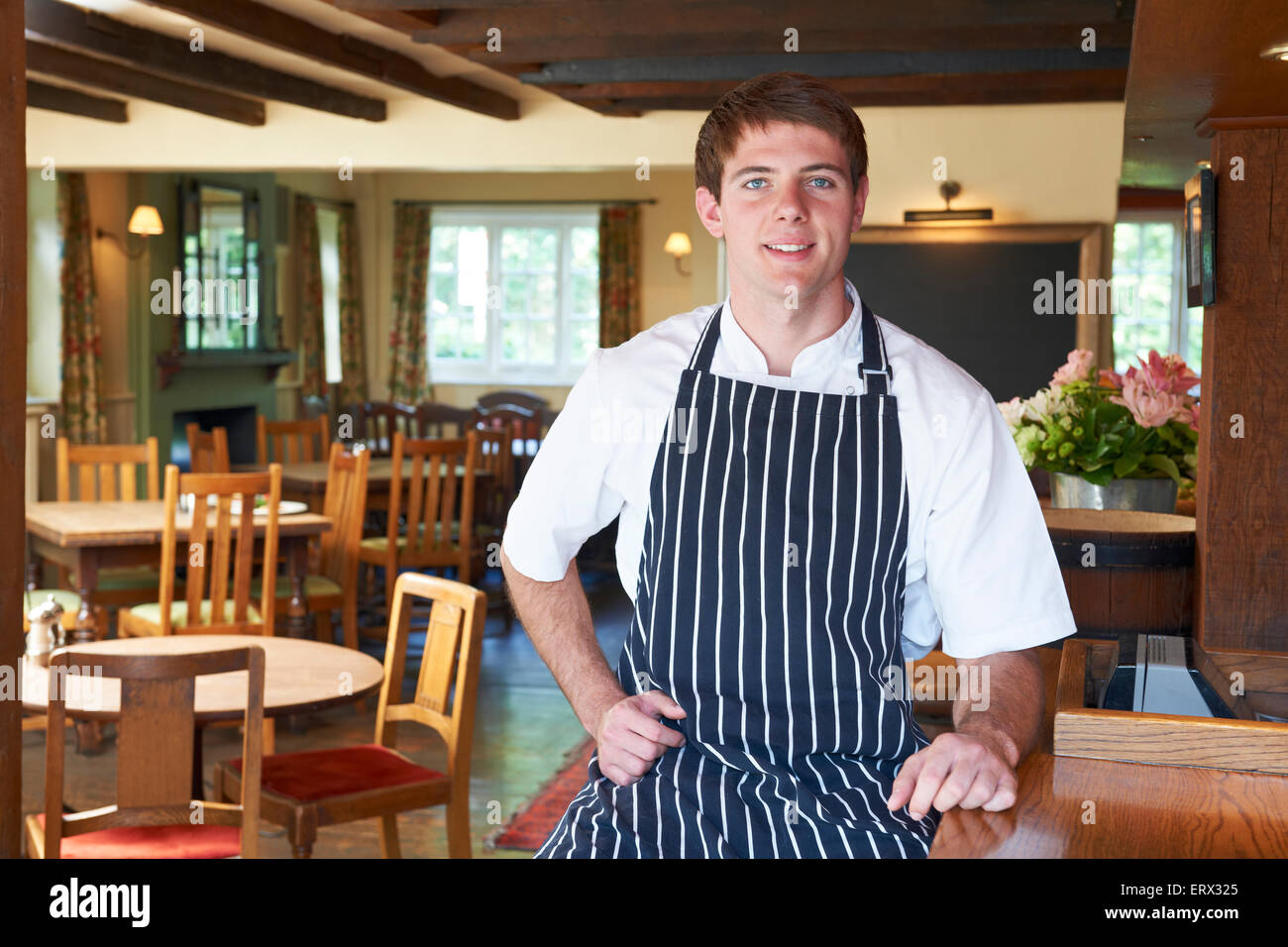 Chef Wearing Whites And Apron Sitting In Restaurant Stock Photo