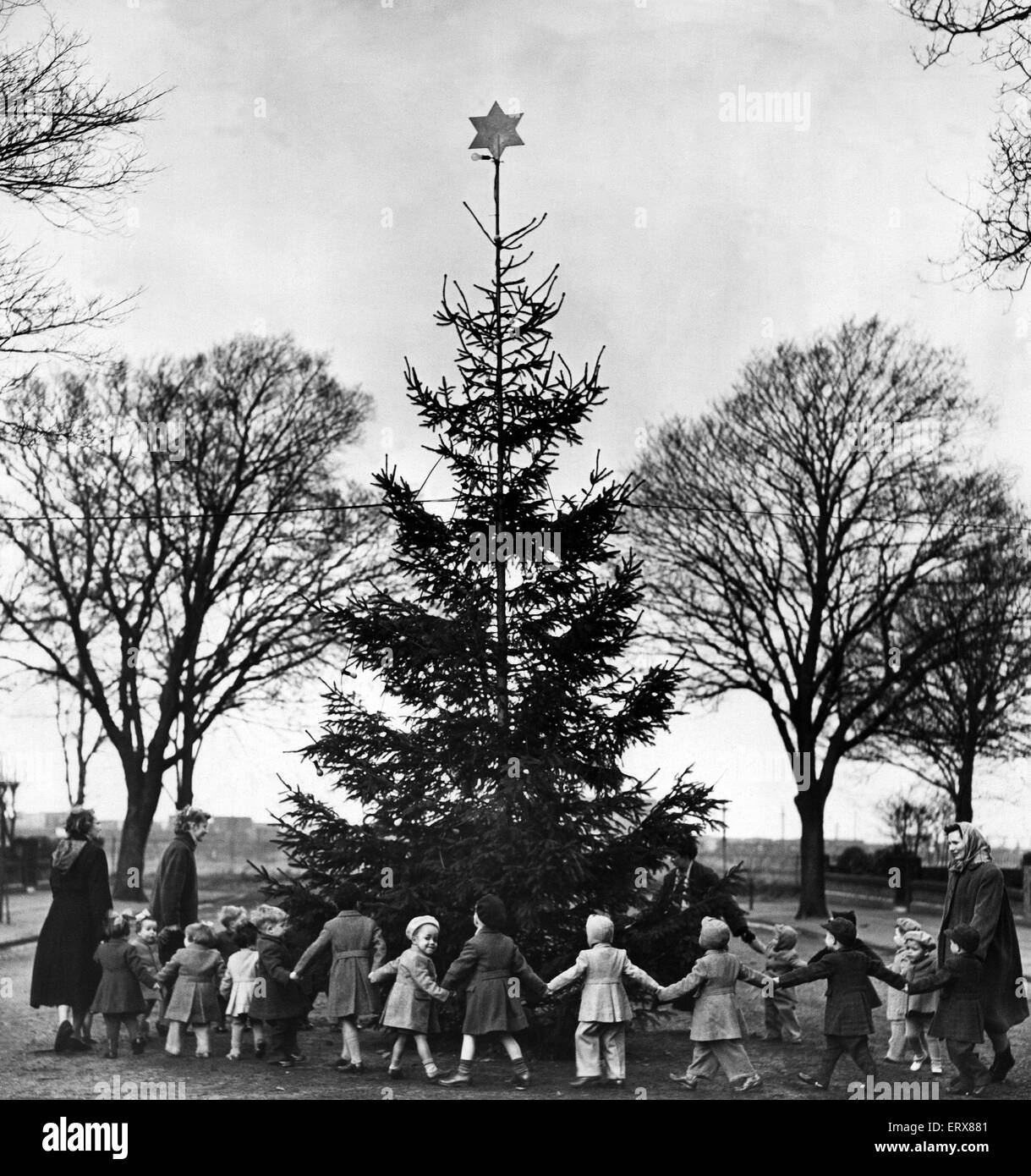 Orphans fropm Liverpool Cottage Homes, Fazakerley, dance round a Christmas tree. Liverpool, Merseyside, 13th December 1956 Stock Photo