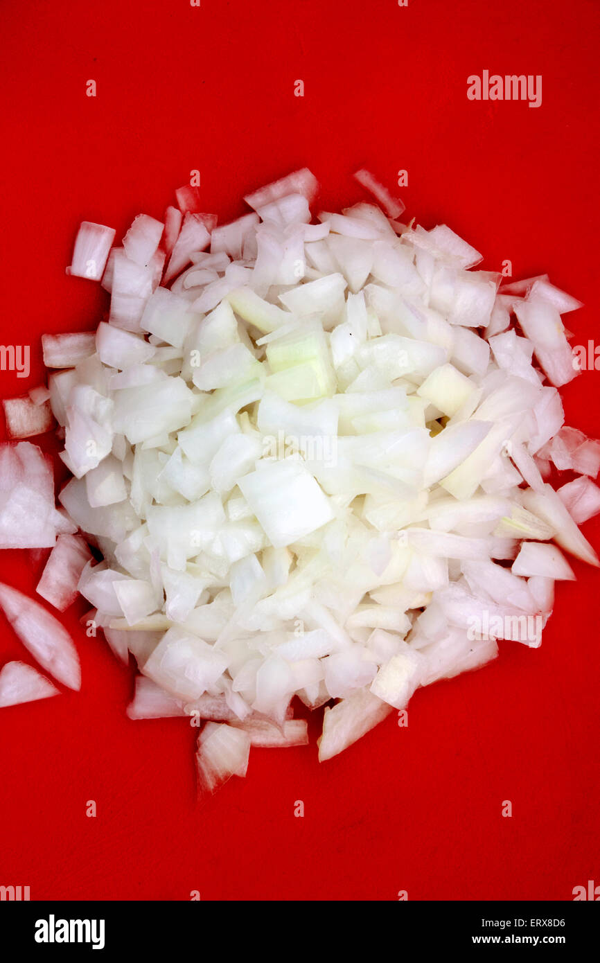 a bunch of chopped onion over a red board Stock Photo