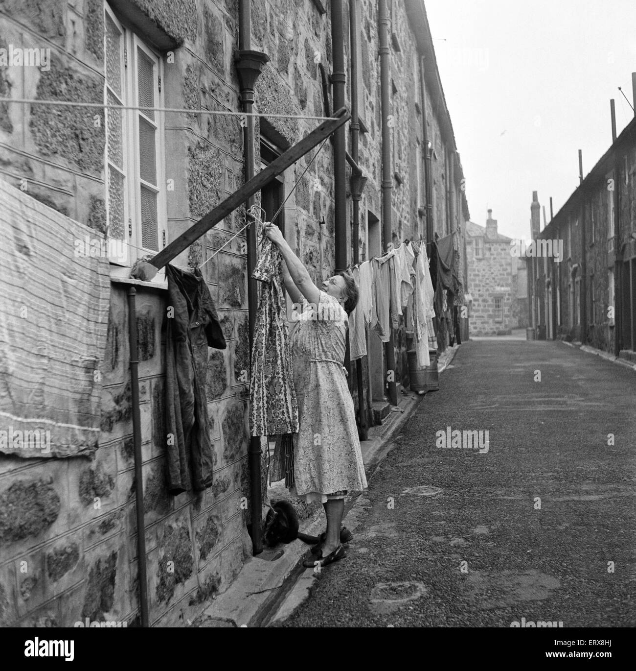 A woman hanging out her washing in a street in St Ives, Cornwall. 15th February 1954. Stock Photo