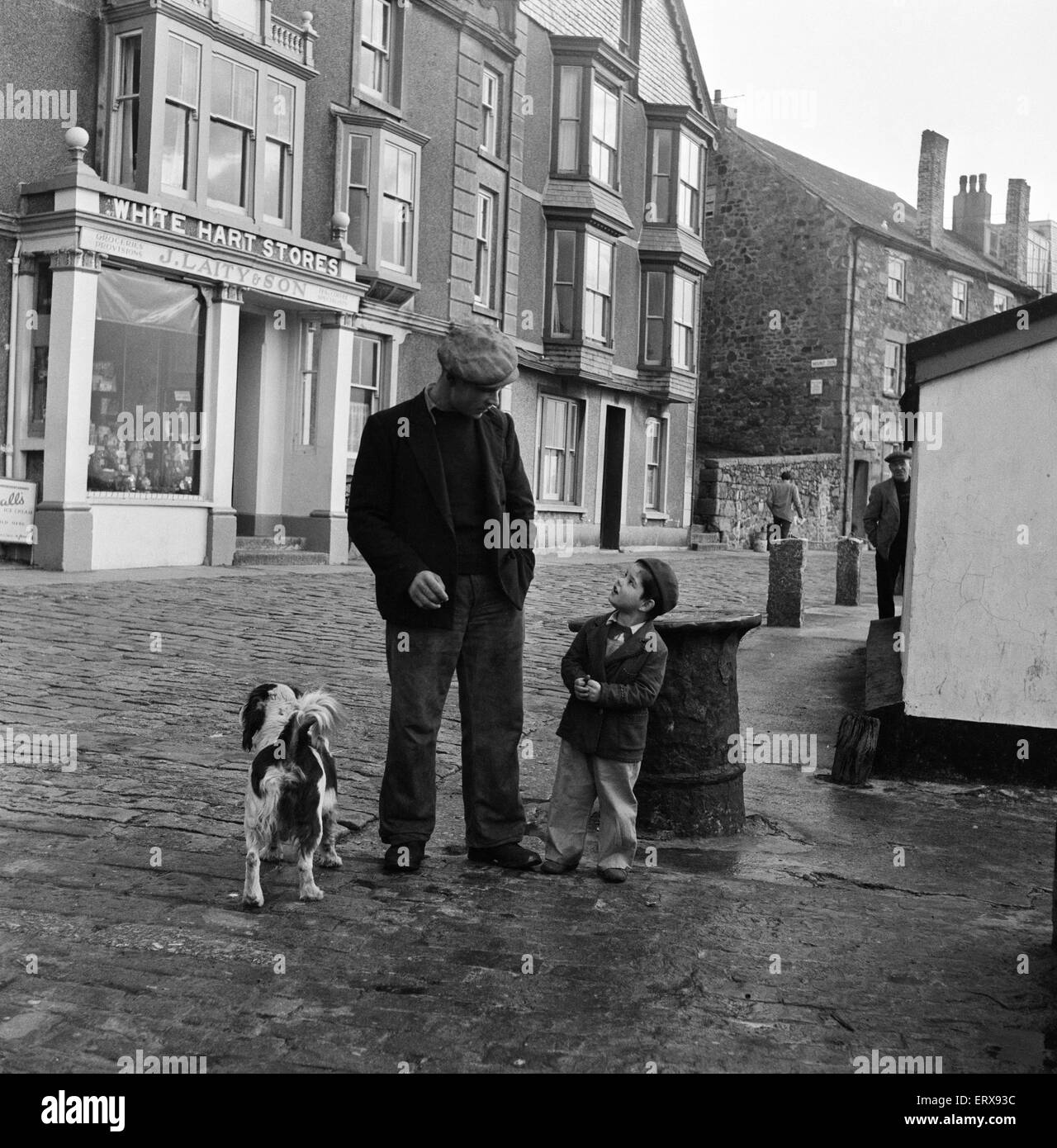 A fisherman and his son. Returning after a weeks absence on a fishing trip in the stormy Irish sea, Stanley Beazley takes his son Geoffrey, 3 years, and their dog Zanny for a walk on St Ives Wharf. St Ives, Cornwall. 15th February 1954. Stock Photo