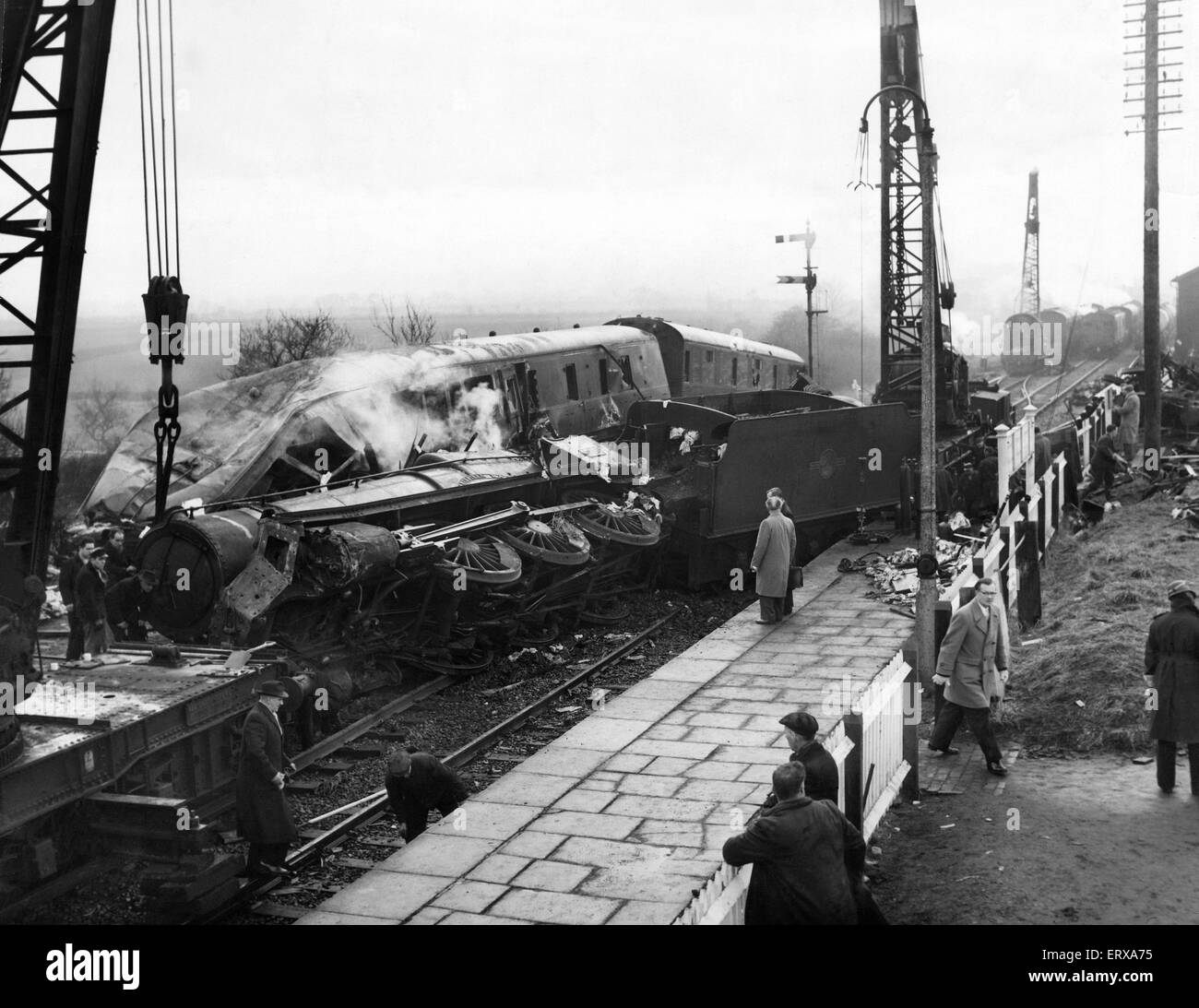 Baschurch train crash: The recover operation at Baschurch railway station following the collision between Wellington to Chester Down express passenger train and a freight train, which had been shunted into a siding for the passenger train to go ahead, which was still partially obstructing the main line. The locomotive of the passenger struck the leading vehicle of the freight train a glancing blow causing the passenger train to overturned on to the Up line between the platforms of the station. Three people were killed and 27 injured as a result of the accident. 13th February 1961 Stock Photo
