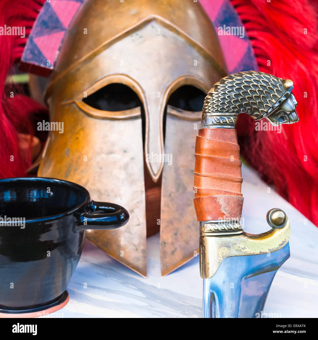 Spartan still-life of a sword, a military helmet and a wine cup on a table. Square photography Stock Photo