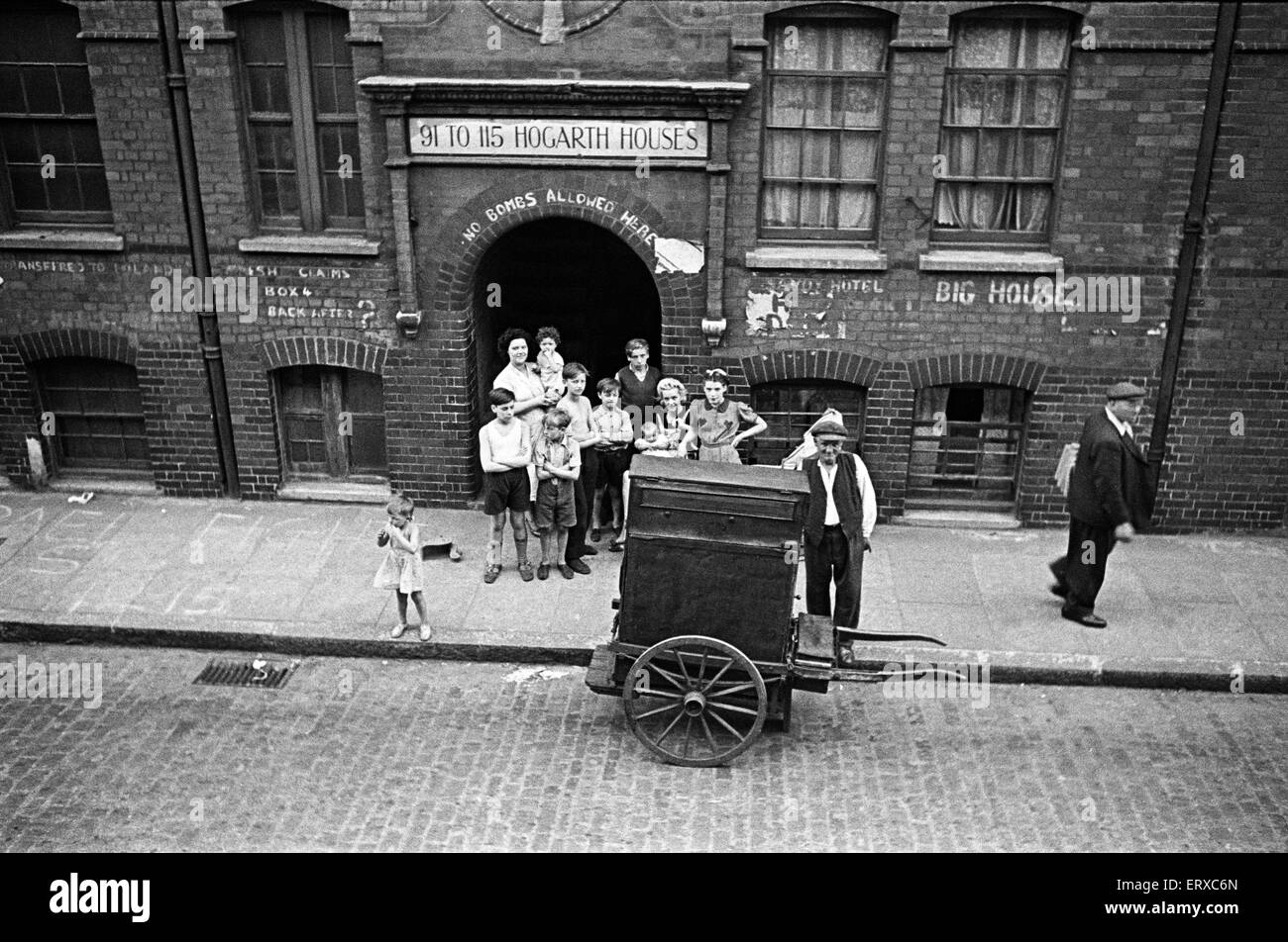 The residents of Hogarth Houses in Whitechapel, East London, watching a barrel organ player.  Circa 1947. Stock Photo