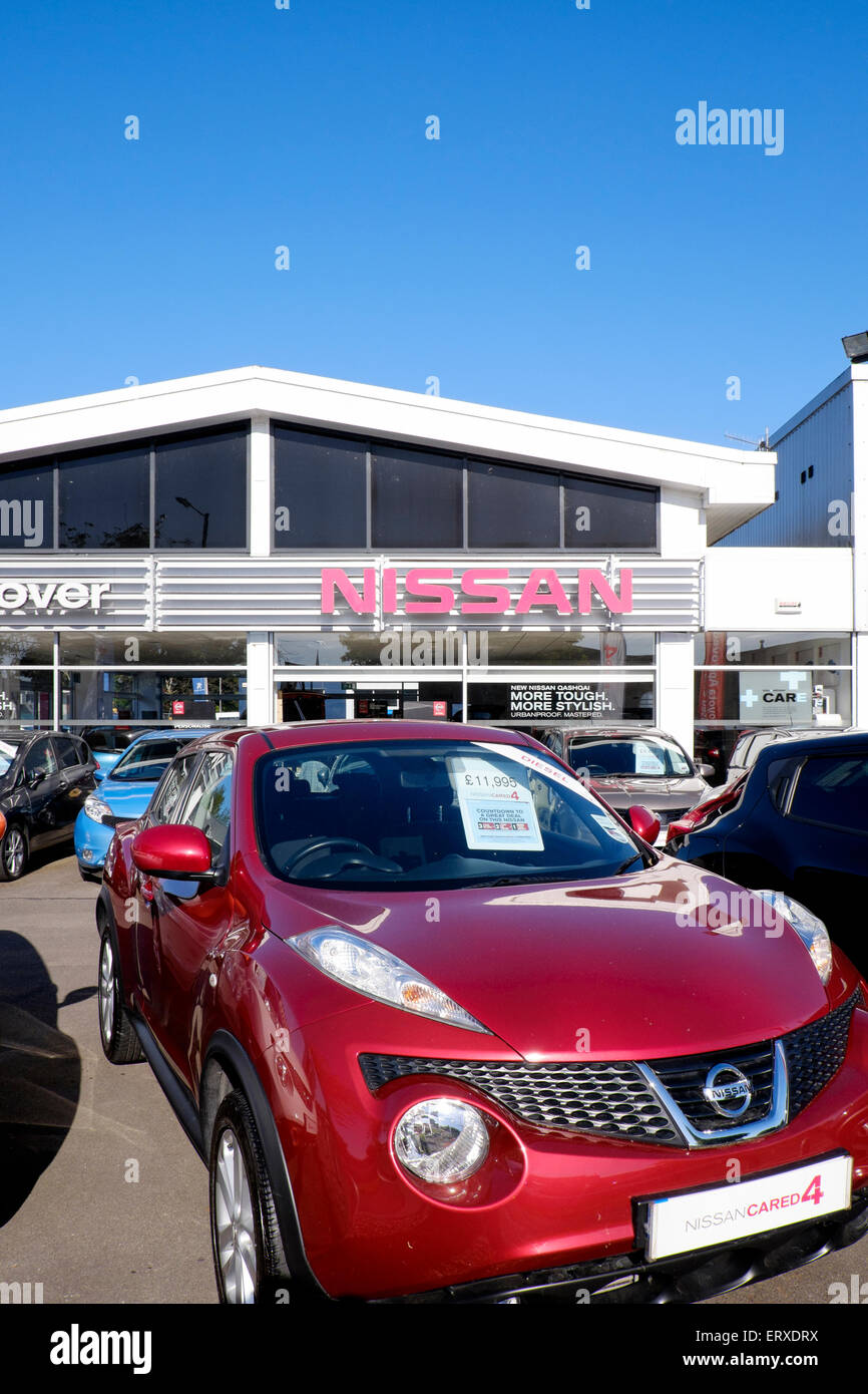 Nissan car dealer UK with four wheel drive model in foreground and blue sky above Stock Photo