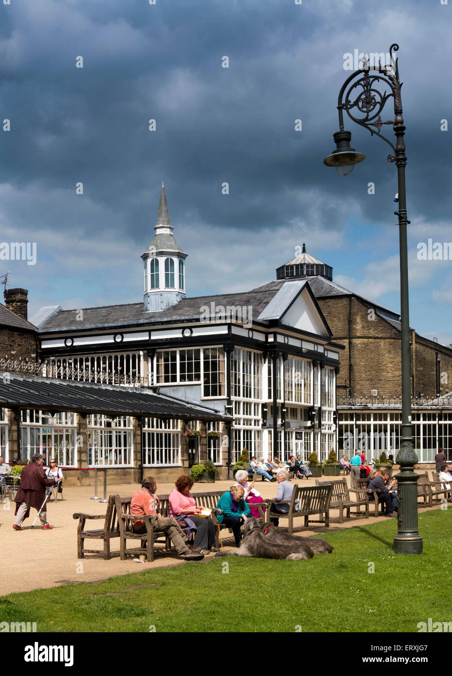 UK, England, Derbyshire, Buxton, Pavilion Gardens, visitors sat in sun outside the Pavilion Stock Photo