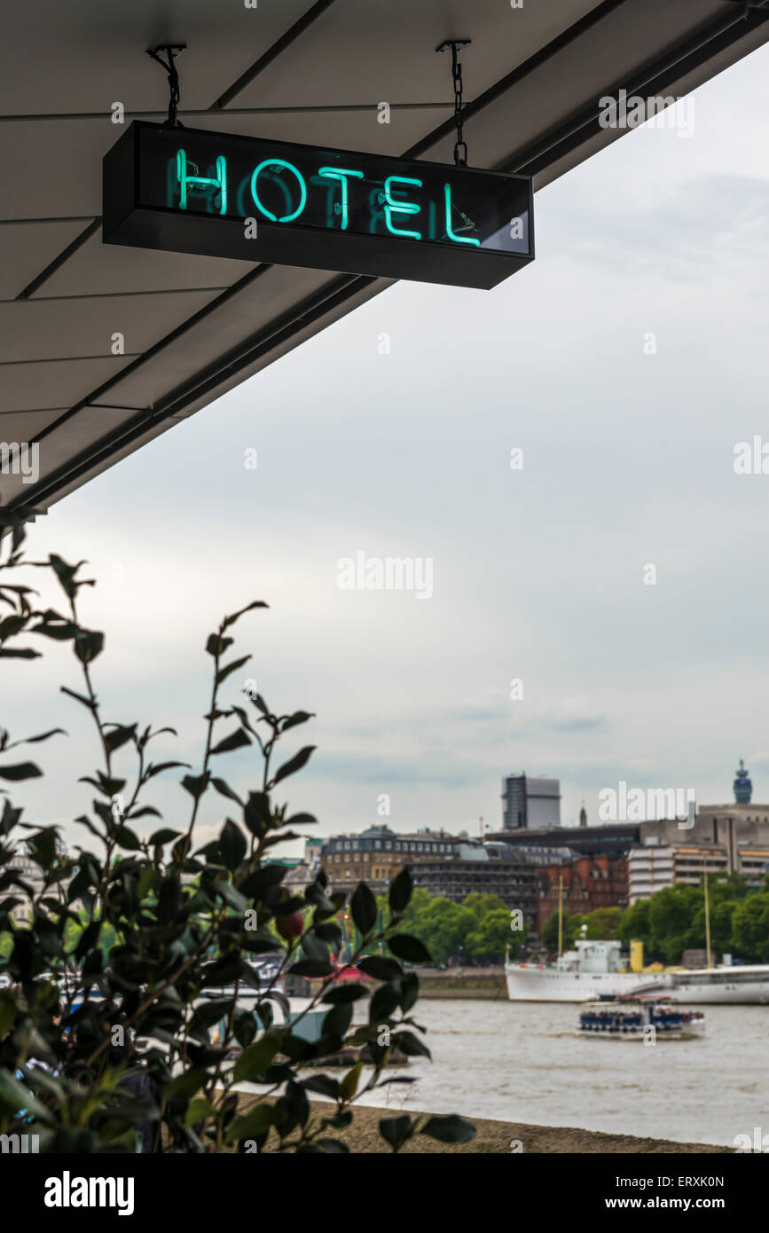 Neon hotel sign hanging from roof with the River Thames and the London ...