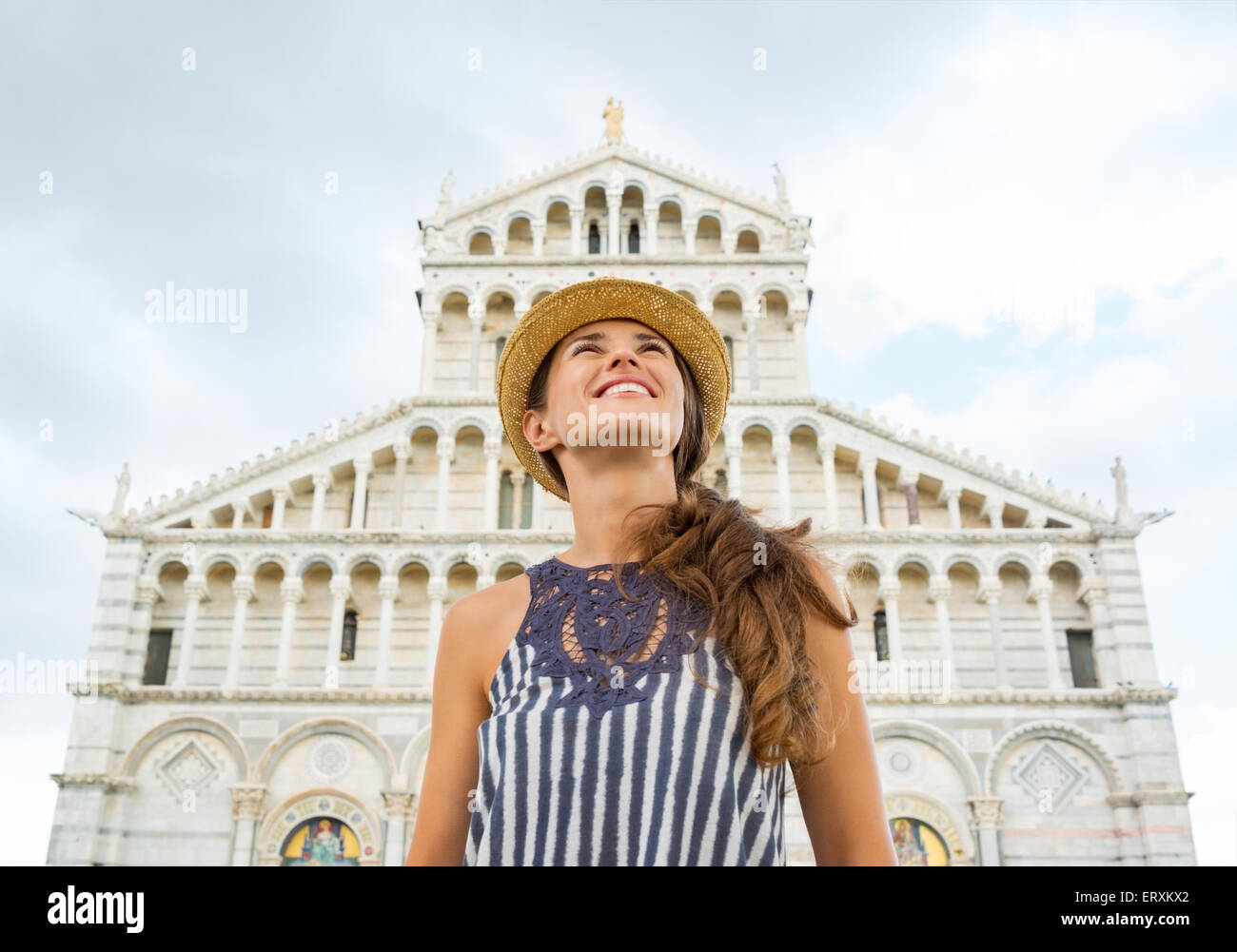 Looking up at the summer sky, a happy woman tourist is smiling as she enjoys the sights in Pisa. Stock Photo