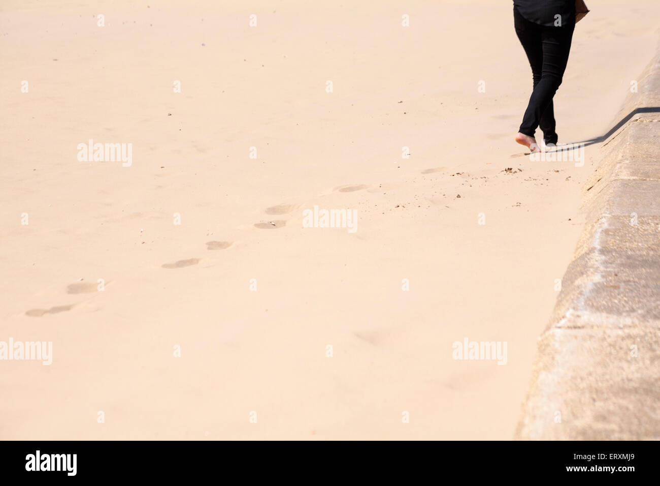 woman walking leaving footprints in the sand at Bournemouth beach in ...