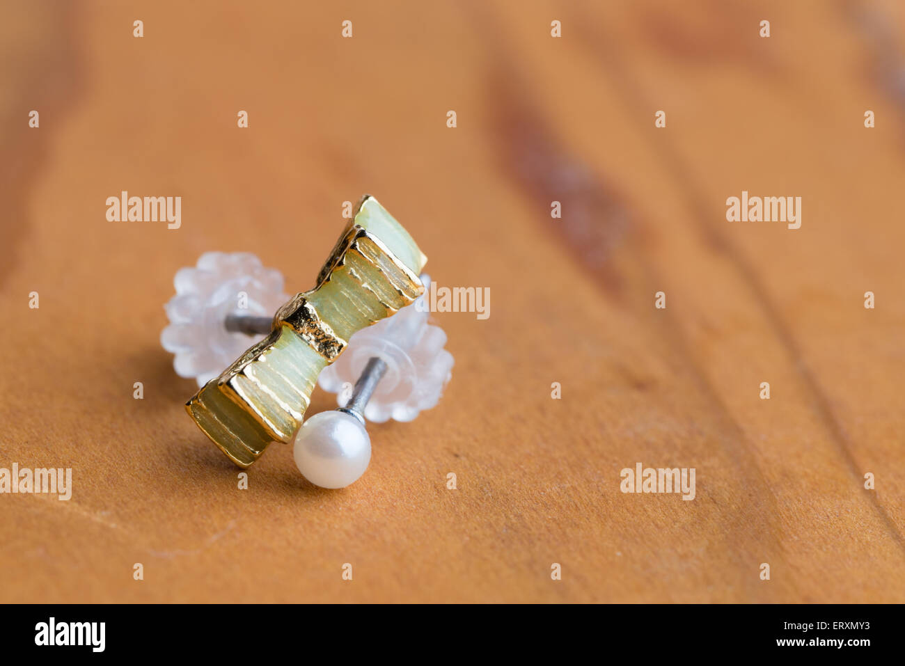 A macro shot of a green ribbon earring and white pearl earring. Stock Photo