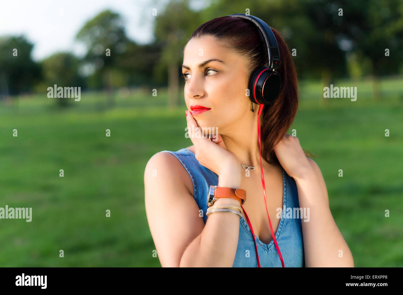 Woman with Headphones in the Park Looking Away Stock Photo