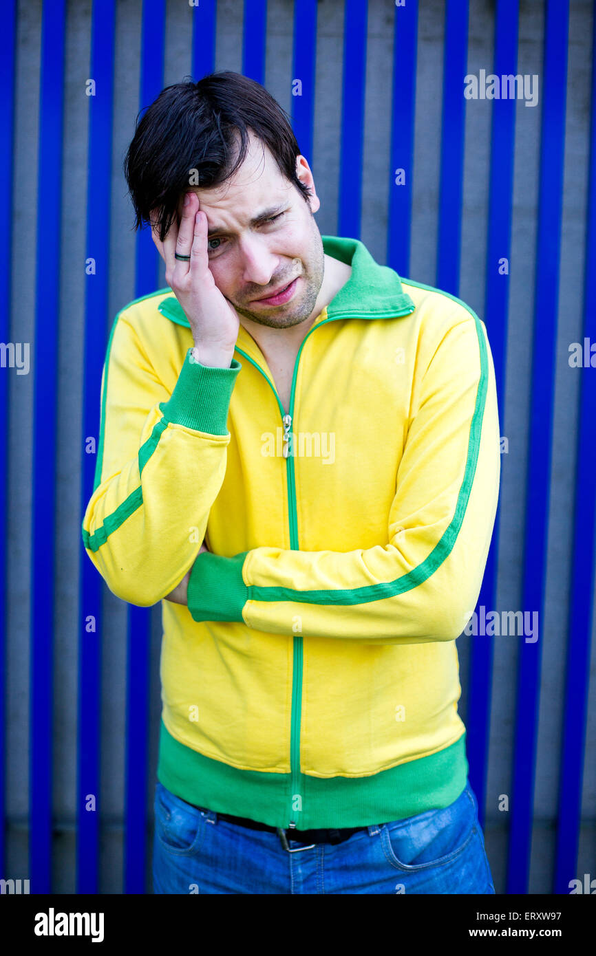 portrait of a man in yellow trikot having a headache Stock Photo