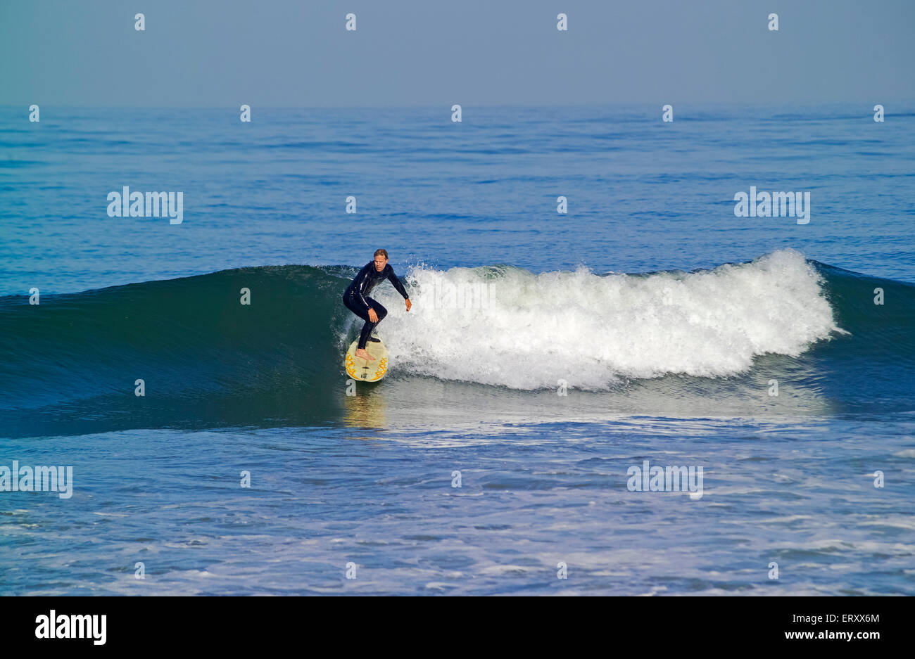 An older male surfer in a black wetsuit catches a Pacific Ocean wave at the famous Trestles surfing spot along San Onofre State Beach at San Clemente on the Southern California coast, USA. A survey in 2009 found surfers at Trestles had a median age of 37 years and surfed there about 100 times during the year. Stock Photo