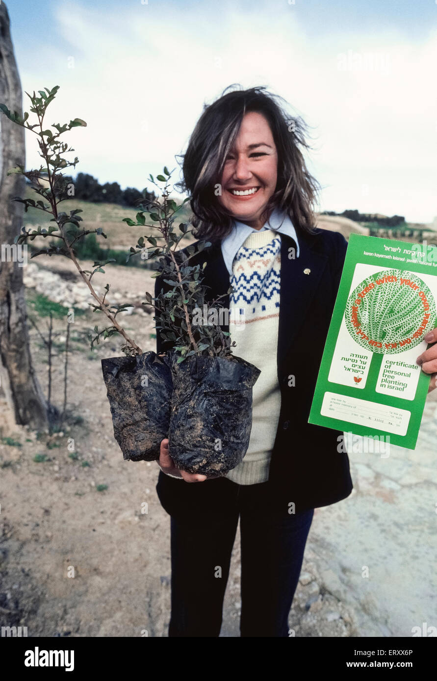 A visitor to Israel shows off the two tiny trees she purchased and is