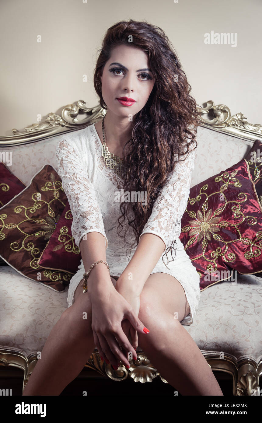 Pretty model girl sitting on victorian sofa posing for camera Stock Photo