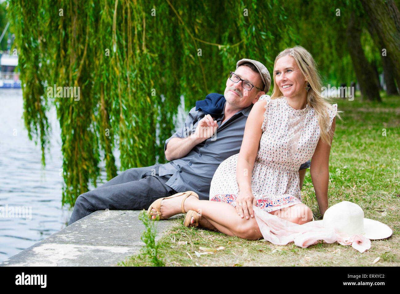 couple sitting in a park alongside the water Stock Photo - Alamy