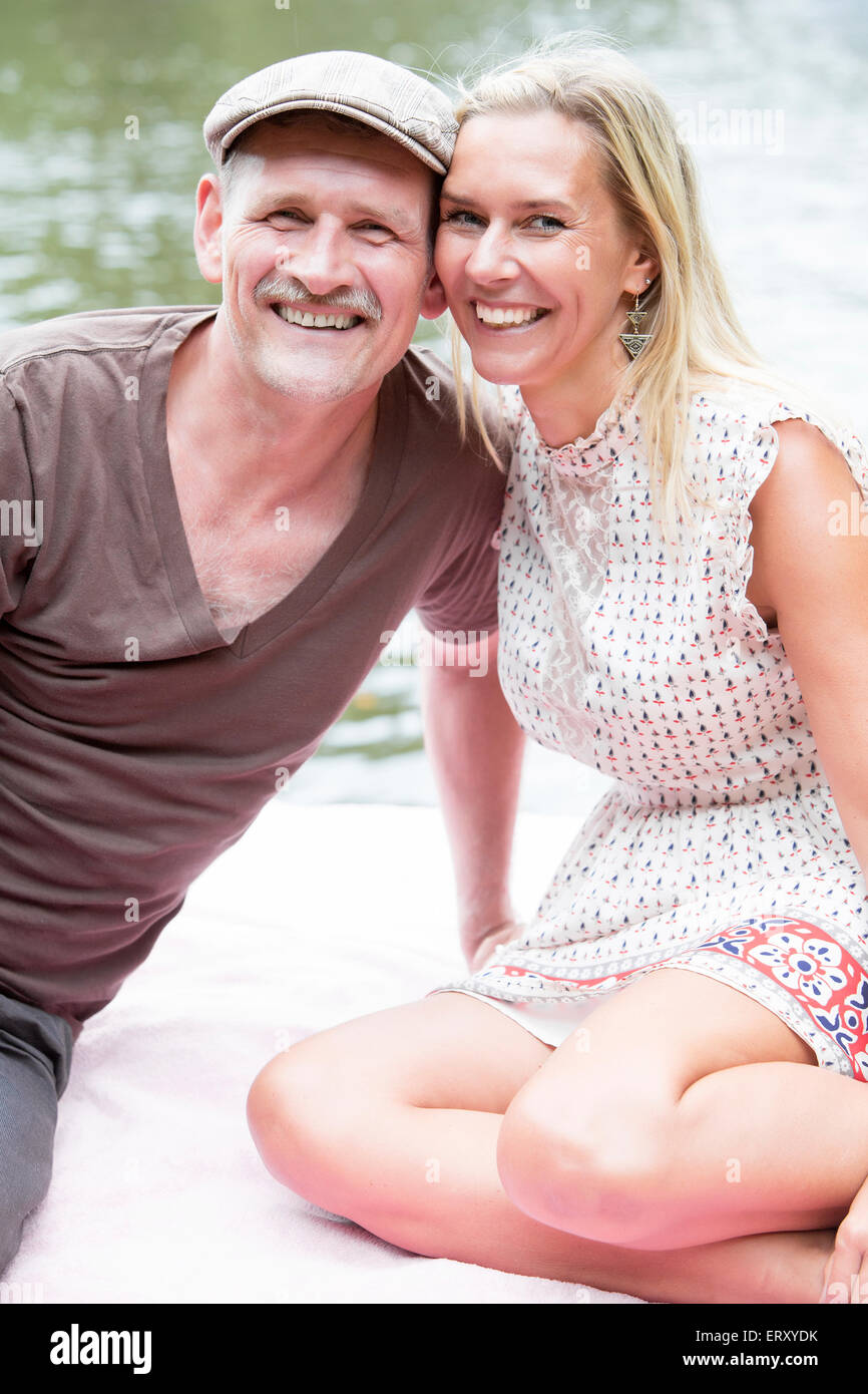 couple sitting in a park alongside the water Stock Photo - Alamy