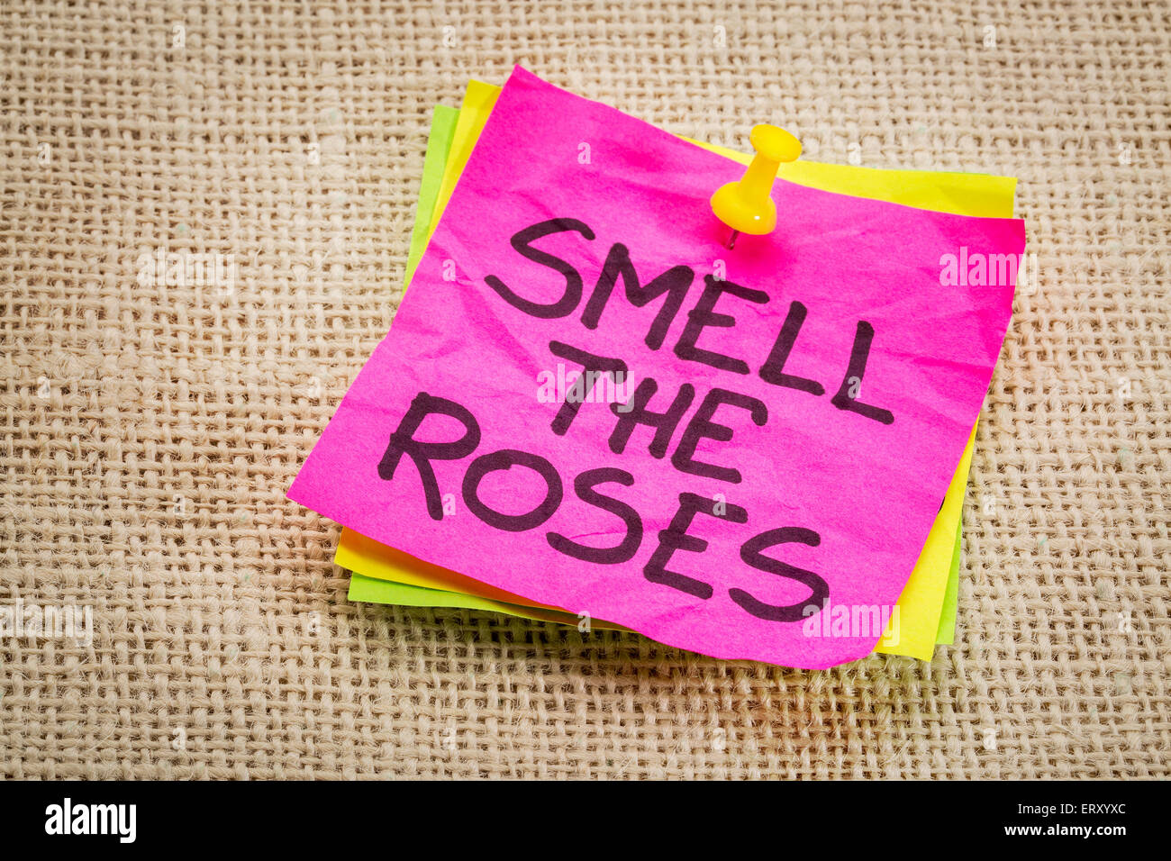 smell the roses - inspirational reminder on a sticky note against burlap canvas Stock Photo