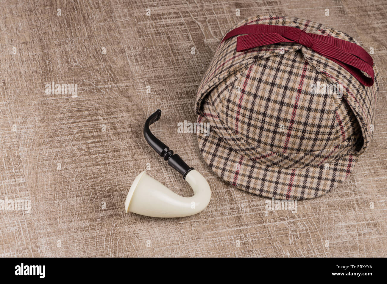 Deerstalker or Sherlock Hat and Tobacco pipe on Old Wooden table. Stock Photo