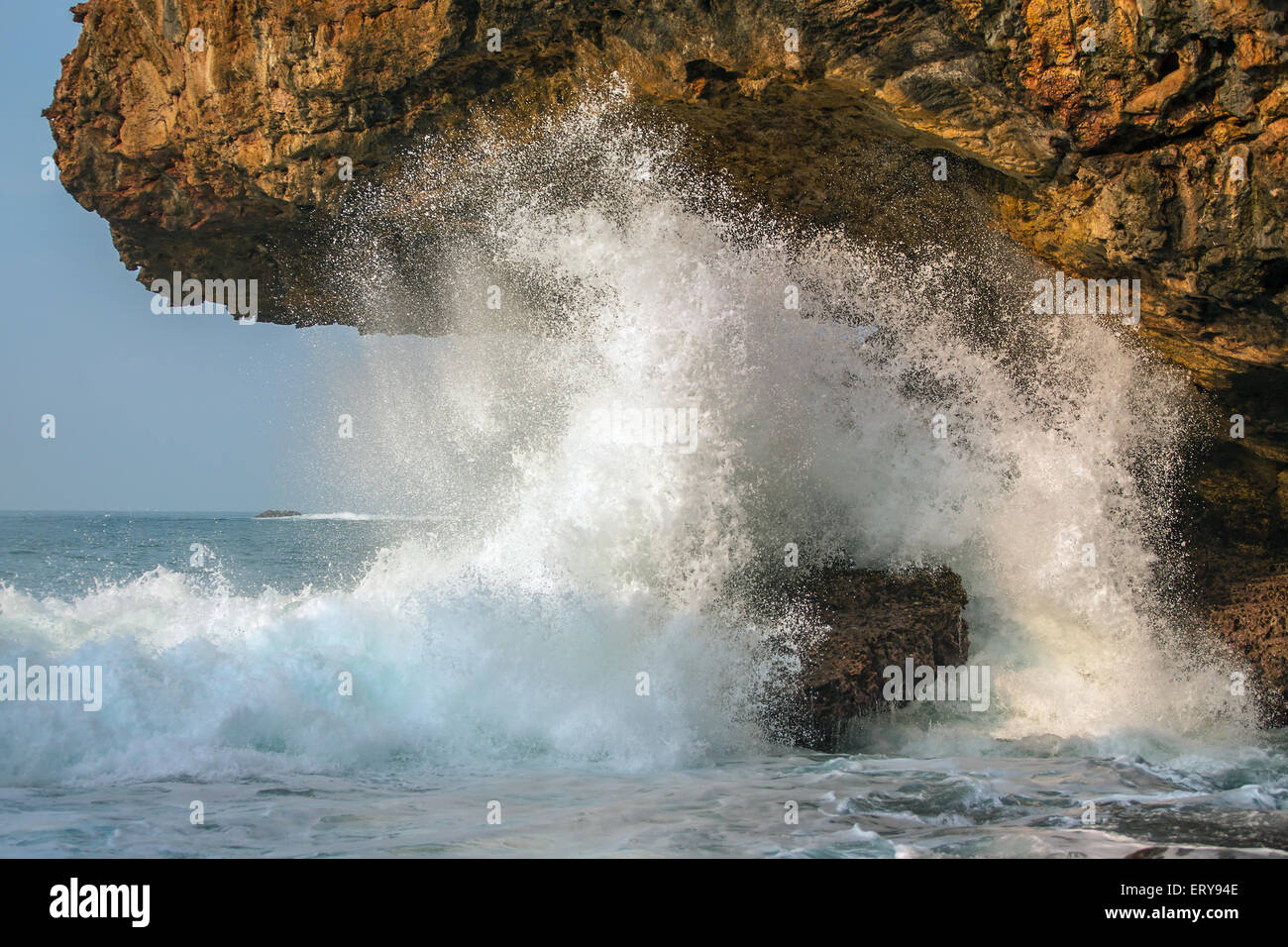 A splashing big wave crashing into the rocks in the rough wild sea water on Java, Indonesia Stock Photo