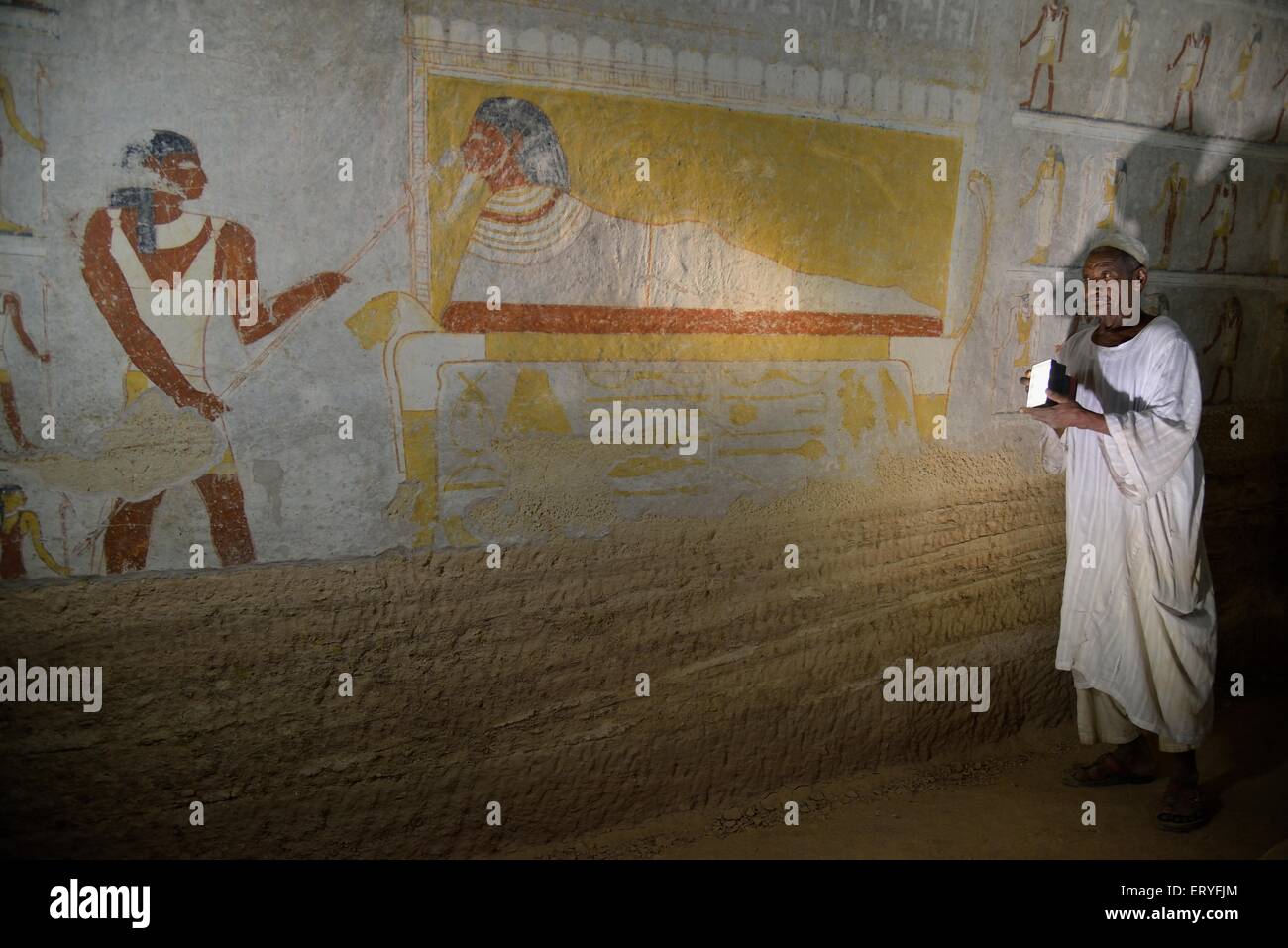 Grave guardian illuminating the mural of King Tanotamun on his deathbed in his grave, el-Kurru, Northern State, Nubia, Sudan Stock Photo
