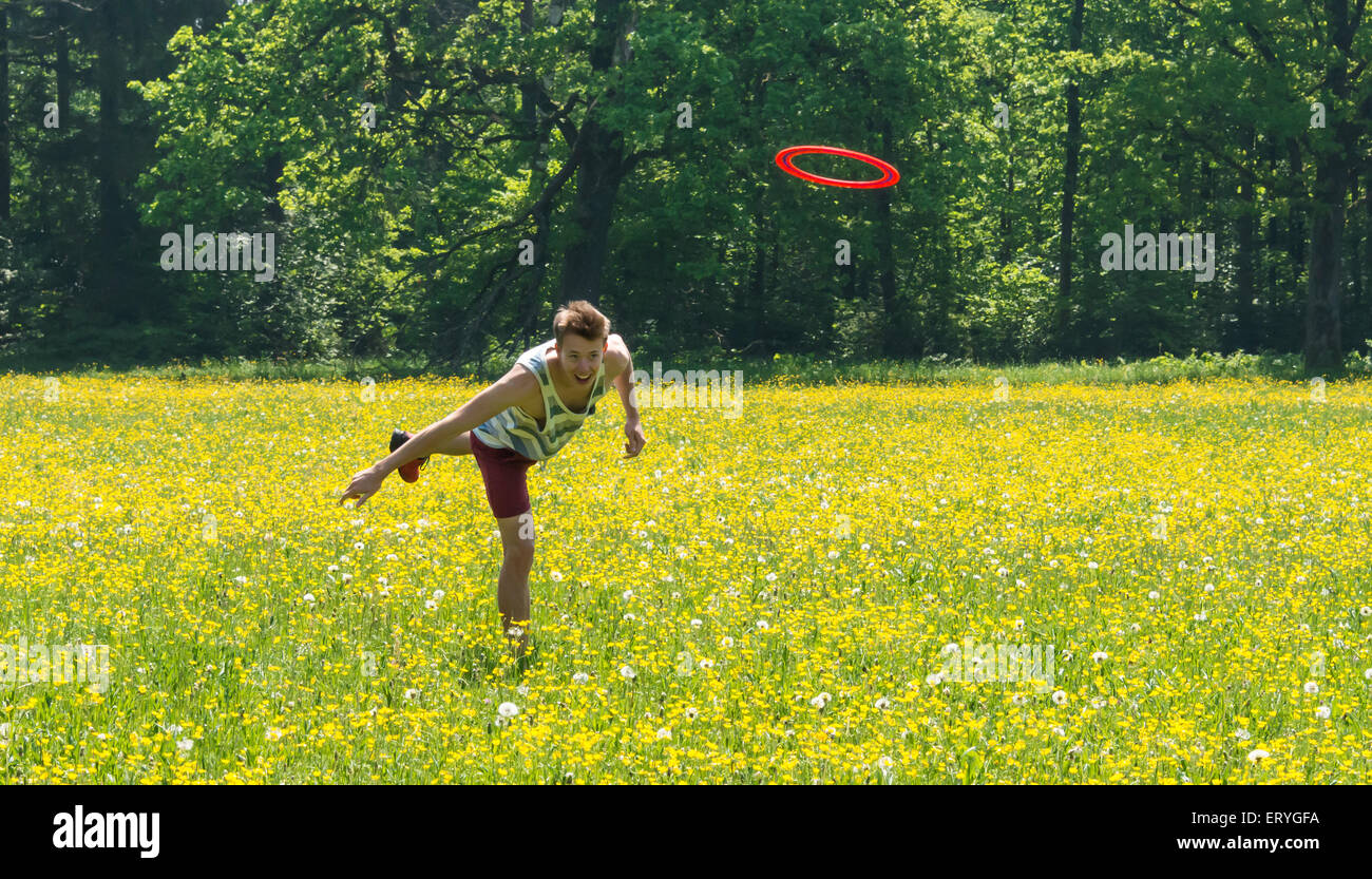 Young man throwing frisbee in meadow, Perlacher Forst, Munich, Bavaria, Germany Stock Photo