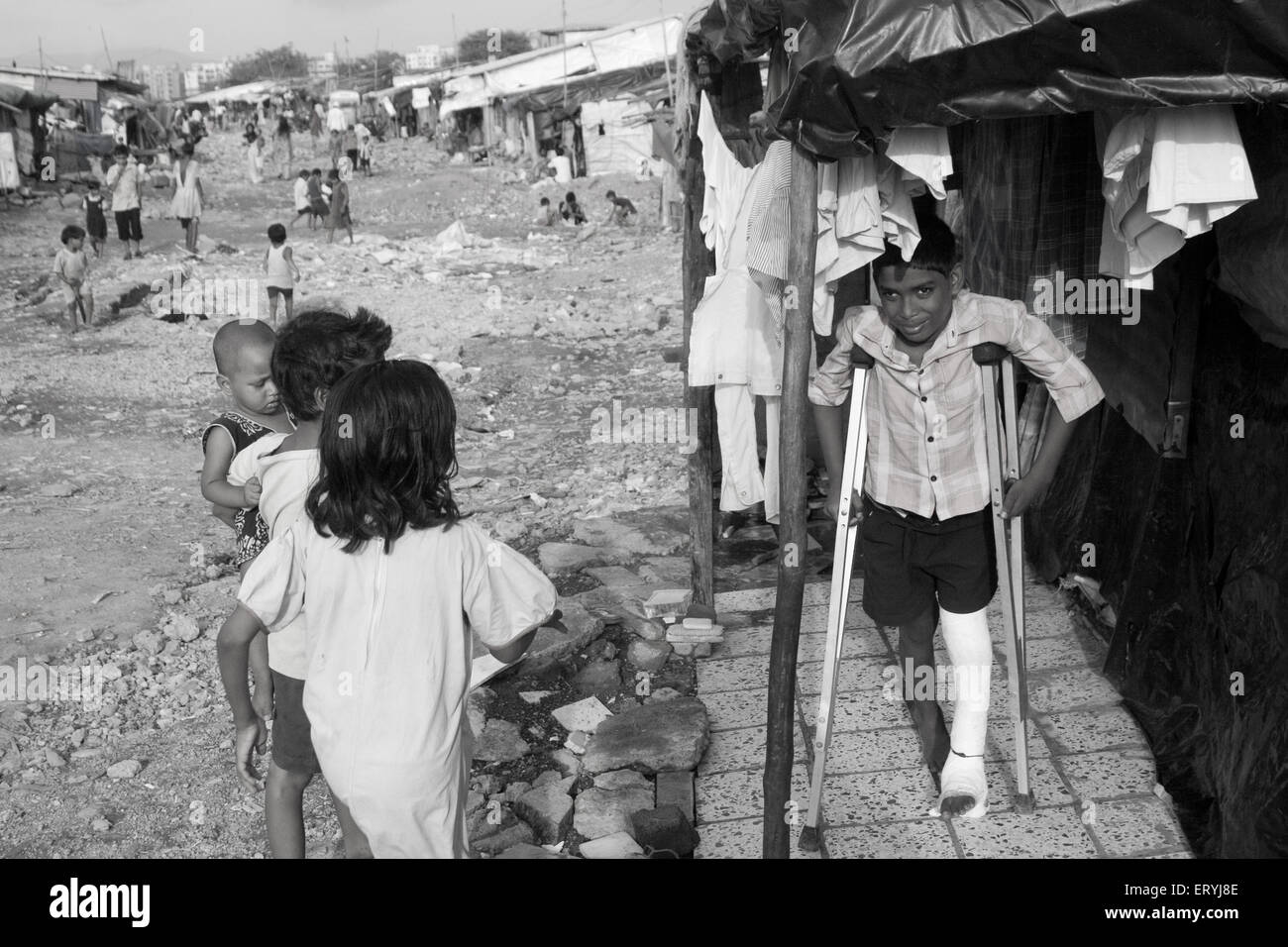 Boy with leg in plaster on crutches ; Malvani slum ; Malad ; Bombay Mumbai ; Maharashtra ; India Stock Photo