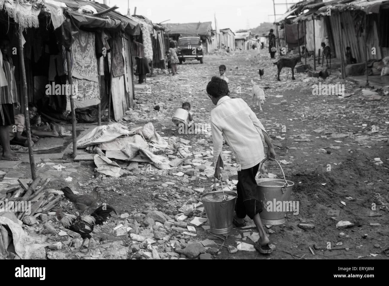 Boy carrying two buckets of water in Malvani slum ; Malad ; Bombay Mumbai ; Maharashtra ; India Stock Photo