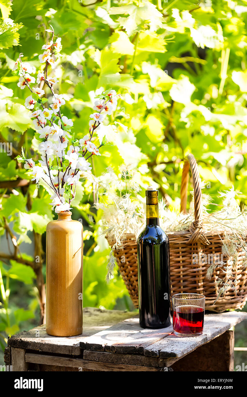 Still life with bottle and glass red wine on background of green ...