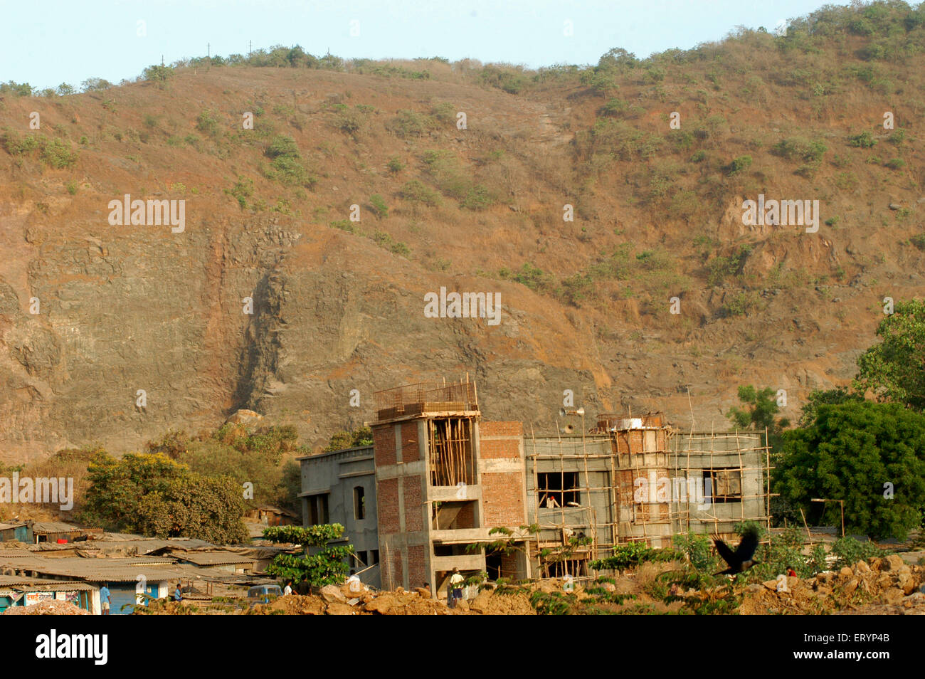 Small hill being destroyed by slowly being destroyed by quarrying and construction to pave way for residential complex in Bombay Stock Photo