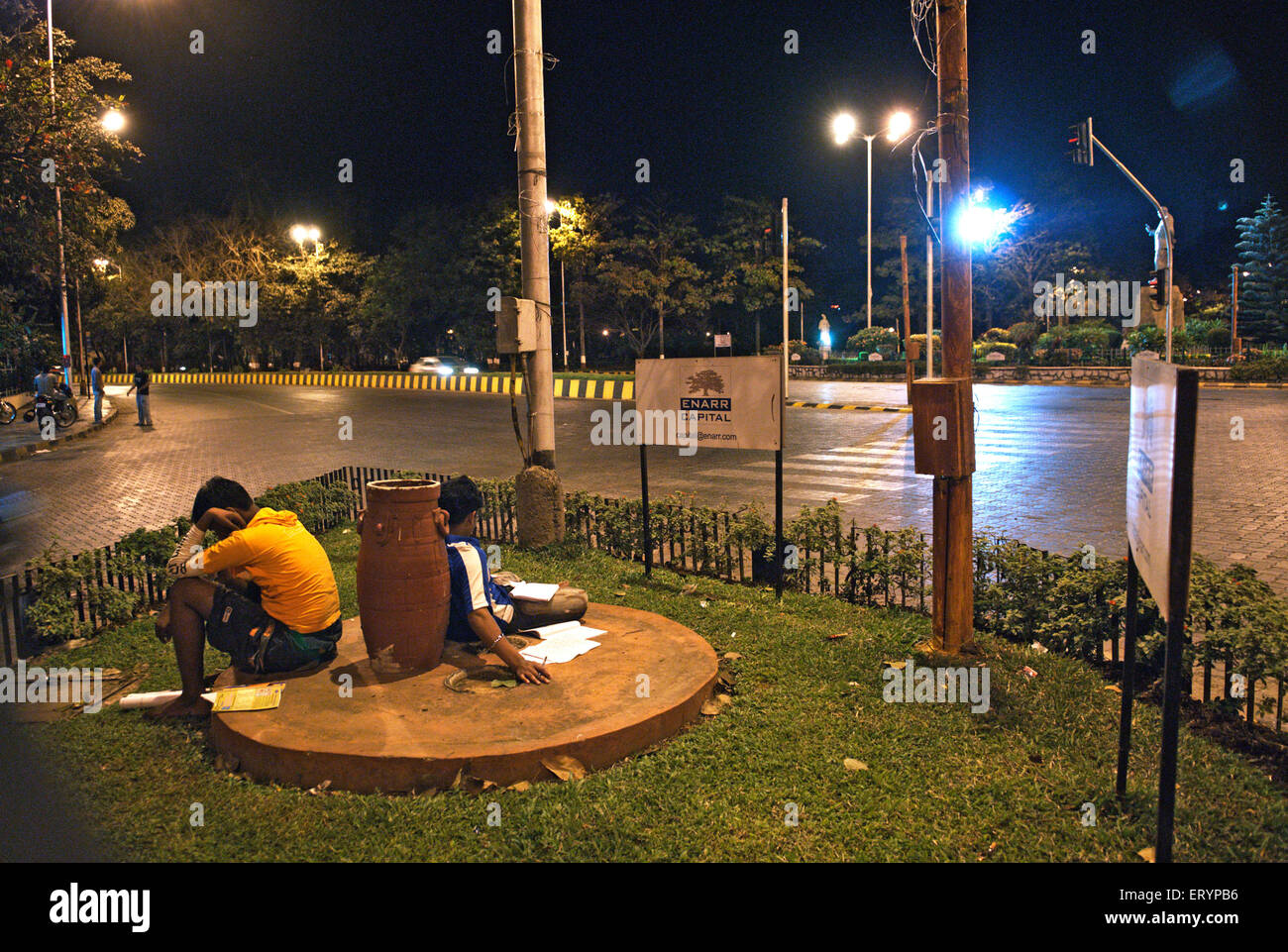 Students studying under street lights in roundabout , Bombay , Mumbai , Maharashtra , India , Asia Stock Photo