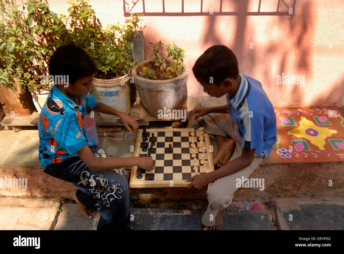 School children play game of chess during their vacations outside their homes in Bombay Mumbai ; Maharashtra ; India Stock Photo